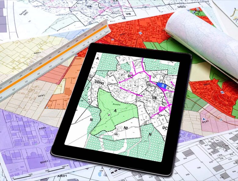 tablet with a map on it on top of paper maps